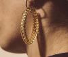 Boucles d'oreilles pendantes originales Chic Alors composées d'un anneau rond en métal doré et d'un grand anneau en résine transparente en forme d'ogive.